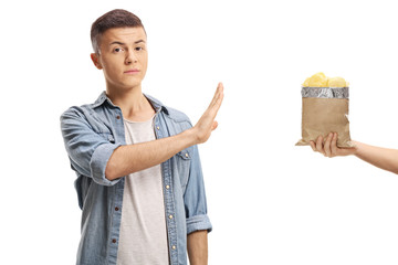 Teenage boy refusing to eat potato crisps