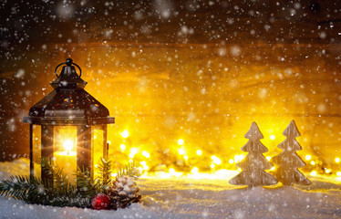 Christmas scene with a lantern, trees, fir branch, snow flakes and blurred lights in front of an...