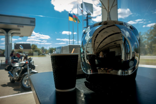 A Biker At A Gas Station Drinks Coffee