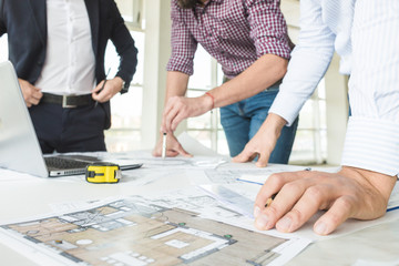 male engineers, architects working at the desk in helmets. Drawings, laptop, roulette on the...