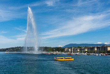 The Jet d'eau, landmark of the city of Geneva, with a yellow taxi boat in front. 500l water/s are...