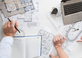male engineers, architects working at the desk in helmets. Drawings, laptop, roulette on the...
