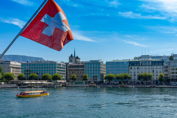 Swiss flag in front of the geneve skyline, cathedrale saint-pierre geneve, yellow boat and a...