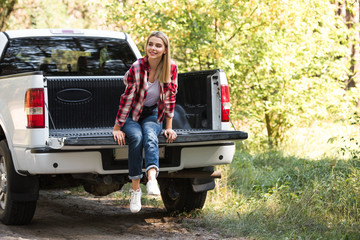attractive young woman looking away and sitting in trunk of pick up car outdoors © LIGHTFIELD STUDIOS