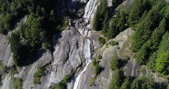 Waterfall on rock wall. Natural park of the Val di Mello, Valtellina, Italian Alps. This valley is famous for sport climbing. Aerial shot made with drone.