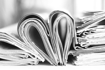Lots of newspapers folded and stacked in pile and heart made of pages with news. Concept for...