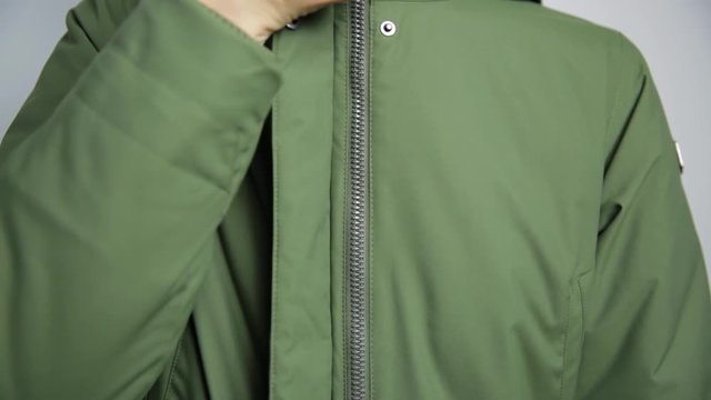 Beautiful women closing winter jacket with zipper.