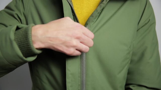 Beautiful women closing winter jacket with zipper.