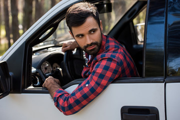 bearded driver holding steering wheel in pickup truck in forest © LIGHTFIELD STUDIOS