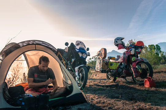 Biker using mobile phone inside tent, Fresno, California, USA