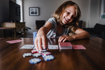 Girl playing cards at table, placing gambling chips