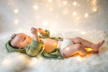 Baby boy lying on furry rug playing with decorative lights