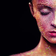 Portrait of Beautiful Woman with Sparkles on her Face. Girl with Art Make-Up in Color Light. Fashion Model with Colorful Makeup