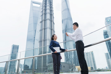 Young businesswoman and man talking in city financial district, Shanghai, China
