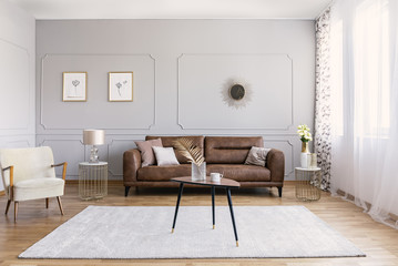 Minimal interior design of living room with brown leather couch, retro armchair coffee table and...