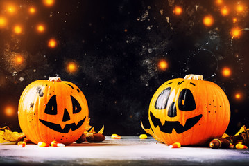Halloween composition with pumpkins lanterns, with lights and fallen leaves on a dark blue...
