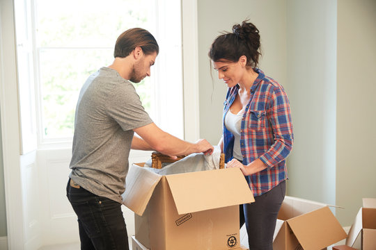 Couple packing mirror into cardboard box