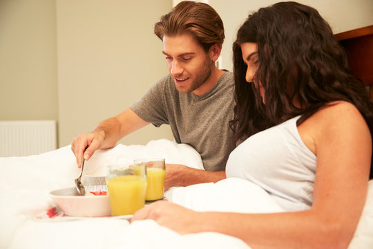 Couple sharing fruit and orange juice breakfast in bed - Powered by Adobe