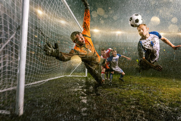 Soccer players performs an action play on a professional night rain stadium. Dirty player in rain...