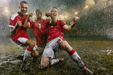 Soccer players on professional soccer night rain stadium. Three dirty players in rain drops...