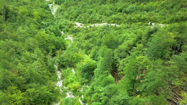 Aerial: Drone landing in beautiful valley Logarska dolina in Slovenia. Going down towards rocky river bed.