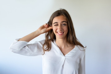 Positive funny young woman adjusting ear to listen better. Cheerful attractive girl with frowning...