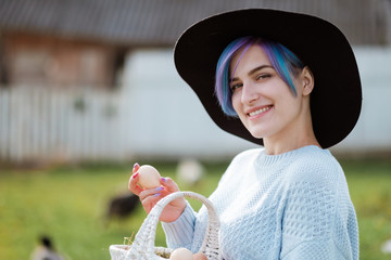 Young beautiful girl in a village holding a basket with chicken eggs. Autumn day, green grass, on...