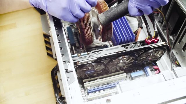 Crane shot. Close up repairing of computer. Cleaning computer system unit from dust with a vacuum cleaner