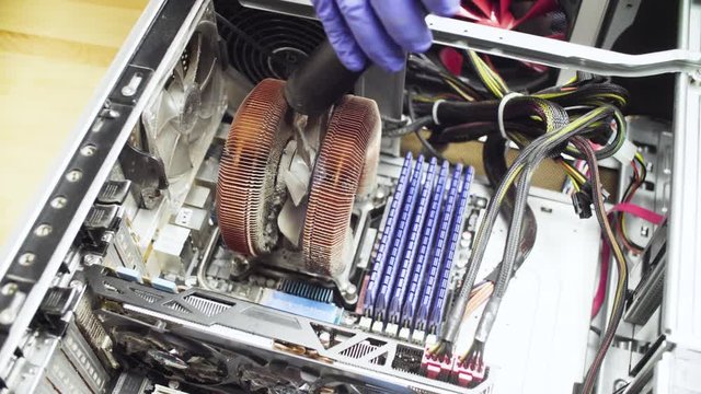 Crane shot. Close up repairing of computer. Cleaning computer system unit from dust with a vacuum cleaner