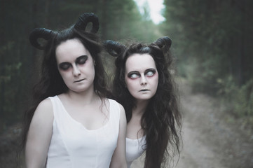 Two twins demons with horns in forest