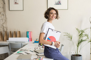 Young smiling woman with short curly hair in wireless earphones