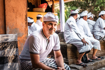 European man in traditional balinese clothes on a big ceremony in Tirta Empul Temple. Bali island.