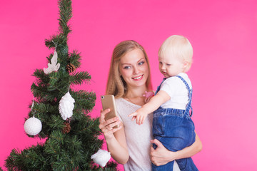 Mother and little daughter taking a selfie near Christmas tree