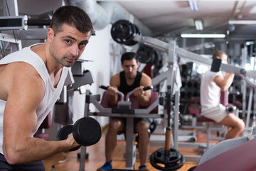 Guy during workout in gym with dumbbells