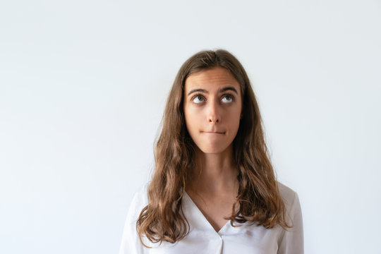 Portrait Of Pensive Female Manager Thinking About New Project And Looking Up. Brunette Elegant Thoughtful Young Woman In White Blouse Rolling Eyes. Isolated On White. Concentration Concept