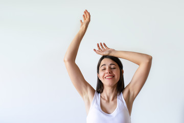 Smiling young woman dancing with closed eyes. Beautiful woman in white clothes with hands up. Isolated on white. Pleasure concept
