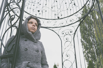 Girl in a coat posing outside in the autumn in gloomy weather, peering thoughtfully into the...