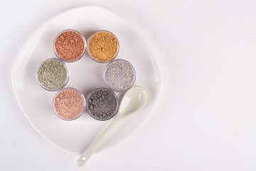 Set of different cosmetic clay mud powders on white background
