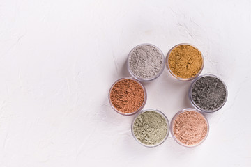 Set of different cosmetic clay mud powders on white background