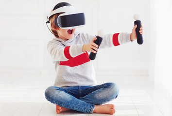excited young boy, kid wearing virtual reality goggles, playing in video game © Olesia Bilkei