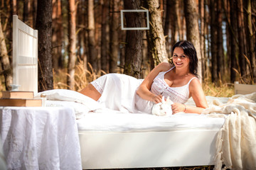 Woman with rabbit in bed in the morning on the nature background of deep forest