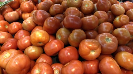 Red and orange tomatoes for sale at a vegetable stall.