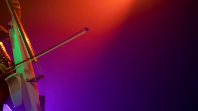 Cellist with electronic cello performs on stage.