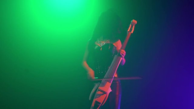 Cellist with electronic cello performs on stage.