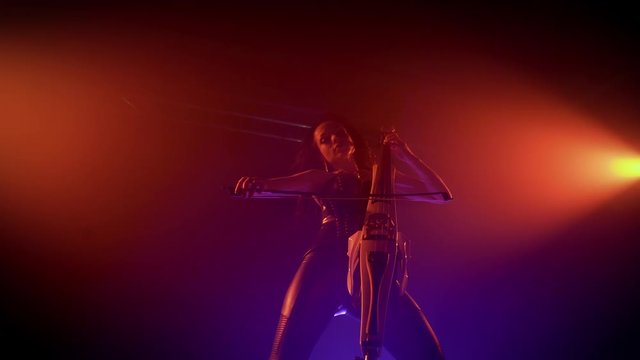 Cellist with electronic cello performs on stage.