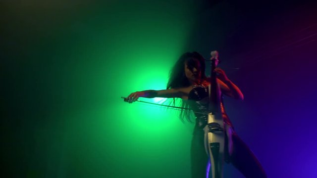 Cellist with electronic cello performs on stage.