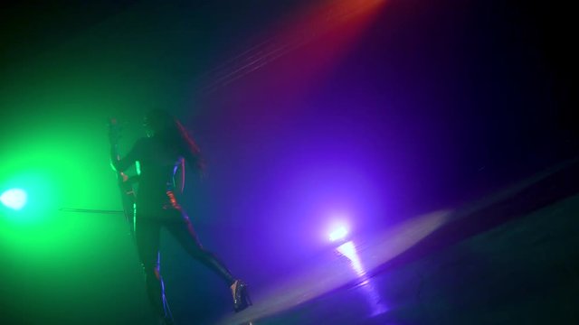 Cellist with electronic cello performs on stage.