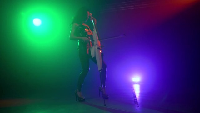 Cellist with electronic cello performs on stage.
