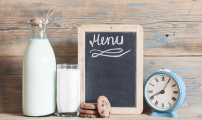 glass of milk on wooden table and blackboard