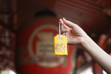 Japanese lucky charm. A hand holding a yellow omamori or A Japanese lucky charm to grant a wish...
